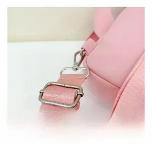 Détail d'une bandoulière rose réglable avec boucles en métal argenté sur un sac pour enfants