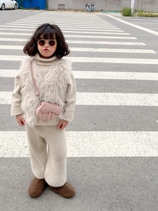 Fillette portant un gilet en fausse fourrure beige avec un mini sac selle rose dehors