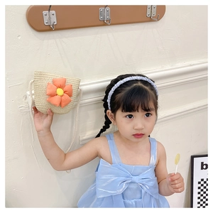 Détail du sac en paille pour enfant avec fleurs en tissu orange et bandoulière en corde blanche