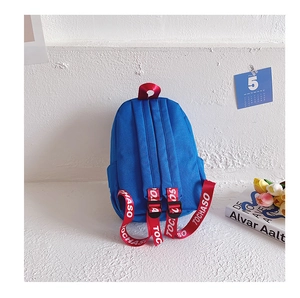 Detail of red shoulder straps with white letters on a blue canvas kids backpack