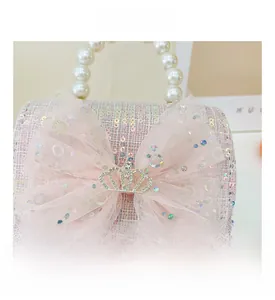 Detail of pink tweed bag featuring sequin texture, mesh bow, and crystal crown ornament