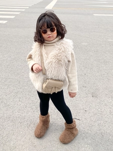 Détail d'un sac besace kaki associé à un gilet en fausse fourrure pour enfant en automne