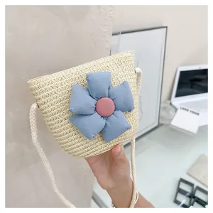 Détail d'un sac en paille pour enfants avec grande fleur en tissu bleu et bandoulière en corde