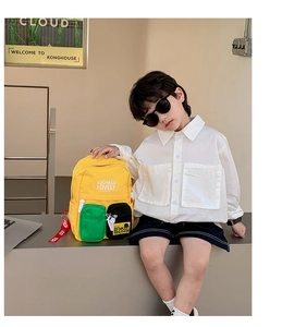 Detail of yellow canvas kids backpack with green mesh pocket and stylish contrast straps