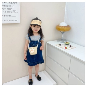 Détail d'une tenue d'été pour fille avec robe en jean, chapeau de paille et sac à fleurs