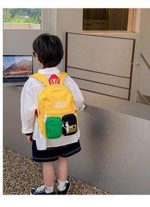 Detail of yellow kids backpack with green mesh pocket and contrast color design