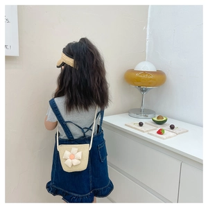 Détail d'un sac en paille pour enfants avec grande fleur 3D blanche et bandoulière tressée