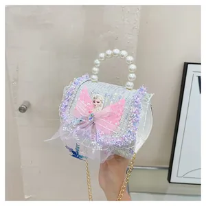 Détail du sac bleu à poignée perlée avec écusson Elsa et décoration de nœud rose