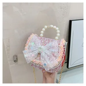 Detail of pink tweed mini bag with pearl handle, lace bow, and crown metal buckle accessory