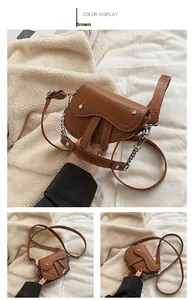 Détail du sac selle marron avec surpiqûres blanches et chaîne en argent élégante