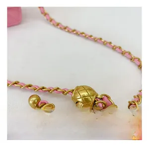 Détail de la bandoulière en cuir rose et chaîne dorée avec boule de réglage vintage