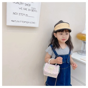 Sac fille tissé rose avec nœud en perles et poignée, porté par une fillette en jean
