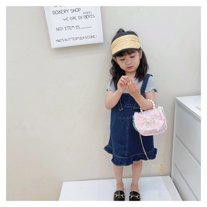 Pink sequin girls handbag with pearl handle and golden chain on a child model