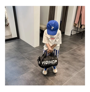 Sac cylindrique en nylon noir pour enfants avec imprimé lettres porté avec une tenue