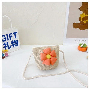 Détail d'un sac bandoulière en paille pour enfants avec une fleur en tissu et texture naturelle