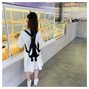 Détail d'un mignon sac à dos lapin en peluche noire avec longues oreilles et pompon blanc