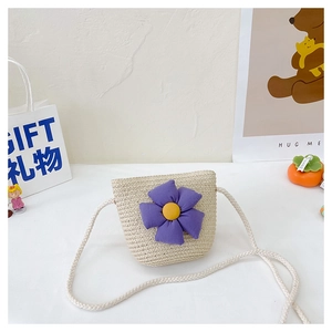 Détail d'un mini sac à bandoulière en paille avec une fleur en tissu violet pour fille
