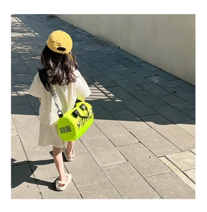 Gros plan sur le sac bandoulière cylindrique vert fluo pour enfants avec logo en noir
