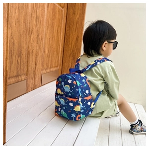 Detail view of child wearing a dark blue dinosaur pattern canvas backpack for toddlers