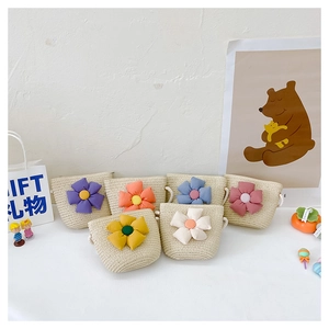 Détail de mini sacs en paille pour enfants avec fleurs colorées en tissu et bandoulières en corde