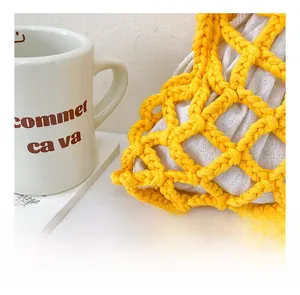 Macro shot of yellow hand-woven hollow bucket bag with cotton drawstring liner