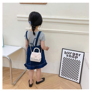 Girl wearing sequined mini bag with pink tulle bow and pearl handle in a cozy room