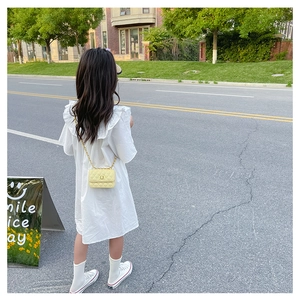 Détail d'une fille en robe blanche à volants avec un sac bandoulière jaune matelassé