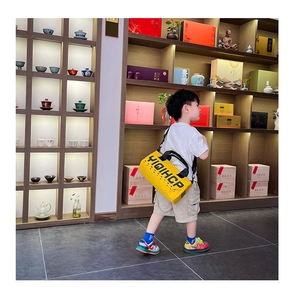 Détail du sac bandoulière jaune en toile pour enfants avec imprimé lettres et sangle réglable