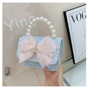 Close-up of blue tweed kids handbag with pink sequin bow and elegant pearl handle