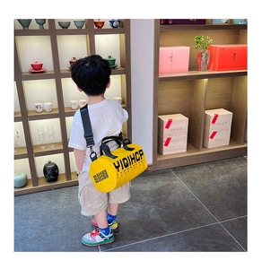 Gros plan sur le sac bandoulière cylindrique jaune pour enfant en toile avec texte noir