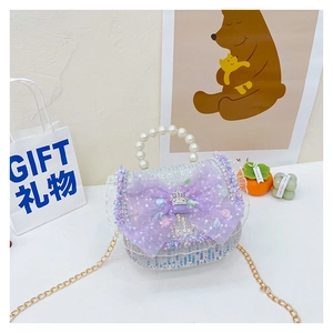 Close-up of purple tweed bag featuring mesh bow, crown ornament and pearl handle