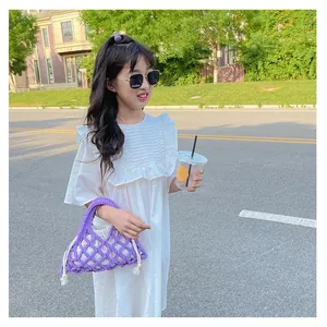 Outdoor shot of a purple crochet bucket bag with a white drawstring liner on a child model