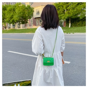 Détail d'un mini sac bandoulière matelassé vert avec chaîne dorée et fermoir métal