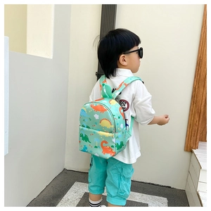 Detail showing toddler backpack size on child model with mint green dinosaur prints