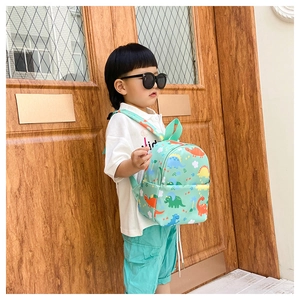 Side view of a light green kids backpack with colorful dinosaur prints on a child