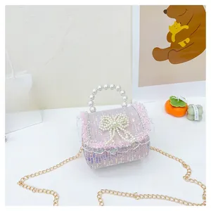 Détail d'un sac fille en tweed rose avec nœud perlé et franges en dentelle blanche