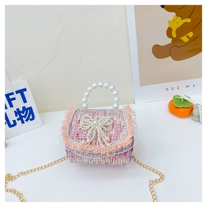 Détail d'un sac à main en tweed rose pour filles avec nœud en perles et chaîne dorée
