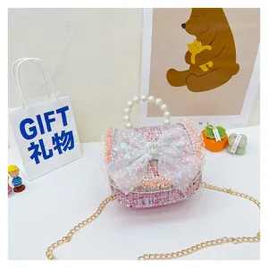 Detail of pink tweed girl's mini bag featuring pearl handle and lace bow decoration