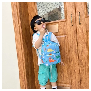 Detail of blue toddler backpack with dinosaur prints showing side pockets and shoulder straps