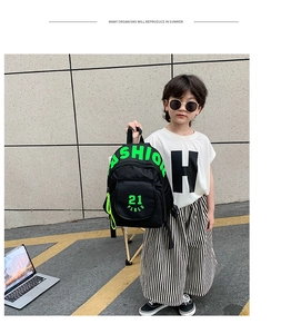 Child wearing black fashion backpack with neon green lettering on street background