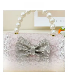 Detail of pink lace handbag with rhinestone bow and pearl beaded handle for girls