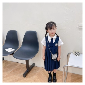Détail de la robe plissée bleu marine et chemise blanche avec un sac à perles mignon