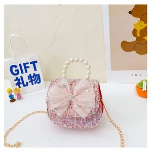 Detail of pink tweed girls bag with large tulle bow, pearl handle and silver crown charm