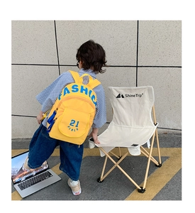 Detailed back view of a yellow canvas backpack worn by a toddler on a street trip