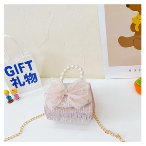 Detail of pink sequin girl's bag with lace bow, pearl handle and crown ornament