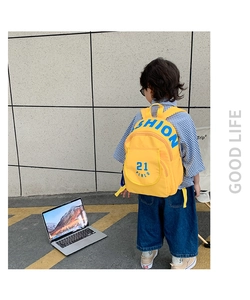 Rear view of a yellow canvas backpack for kids featuring blue fashion print and zippers