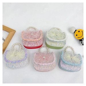 Detail of five mini princess tweed handbags with bows and pearl handles in multiple colors