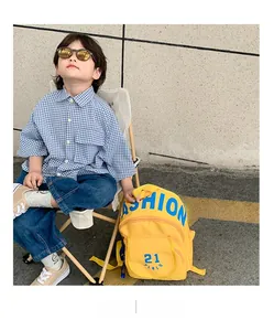 Detail of yellow waterproof nylon kids backpack with Fashion 21 print and zip pockets