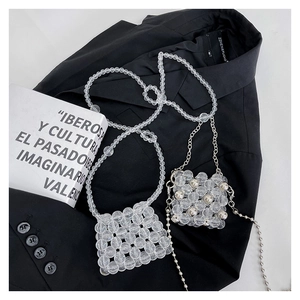 Détail de mini sacs en perles faits main transparents et argentés sur tissu noir
