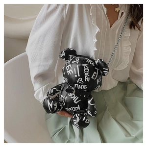 Close-up of black bear-shaped crossbody bag featuring white graffiti prints and chain strap